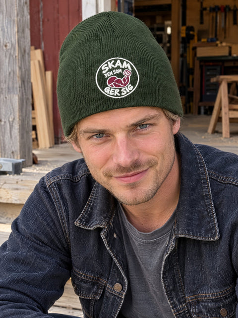 Skam den som ger sig på olivgrön Hatitude Beanie, buren av en yngre vuxen.