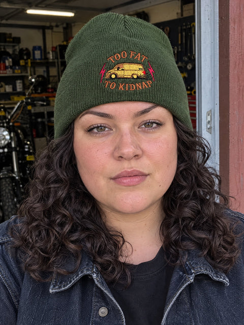 Too Fat To Kidnap på olivgrön Hatitude Beanie, buren av en yngre vuxen.