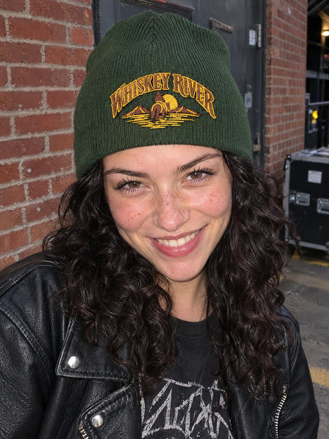 Whiskey River på olivgrön Hatitude Beanie, buren av en yngre vuxen.
